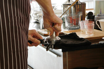 Close up on hand of barista man wearing apron and brewing and grind coffee beans for customers order in cafe and coffee shop. Start up 