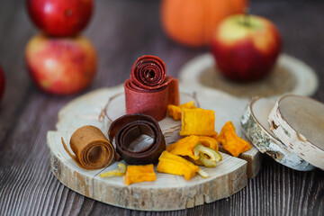 Freshly rolled, homemade fruit leather and dried fruit slices made from organic ingredients are displayed on a rustic table
