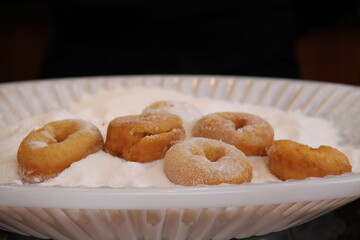 Freshly Made Doughnut Cakes on a Plate of Sugar.