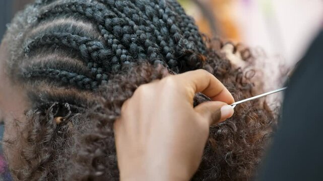 Hairdresser braiding hair with crochet needle in an afro hair salon