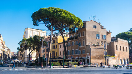 Typical street of Rome during spring with colorful houses beautiful tall green tree and blue sky.