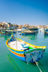 Obraz premium Traditional colorful fishing boats Luzzu in the Harbor of Mediterranean fishing village Marsaxlokk at sunny day, Malta.