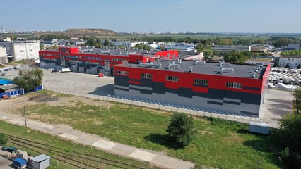 A huge warehouse, a logistics center for storing goods near a huge metropolis. Panoramic view of the city from the industrial area. Huge warehouse in red color.