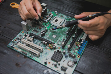 Asian male computer repairman is checking and fixing hardware problems on computers and replacing...
