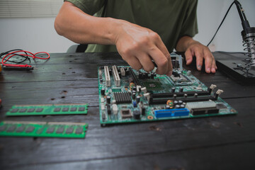 Asian male computer repairman is checking and fixing hardware problems on computers and replacing...