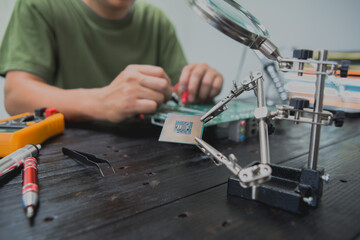Asian male computer repairman is checking and fixing hardware problems on computers and replacing...