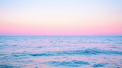 Obraz premium A serene seascape with a soft pink and blue sky at sunset, the ocean is calm and tranquil.