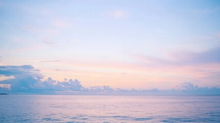 Blurred background of a tranquil seascape with soft pink and blue hues during sunrise or sunset.