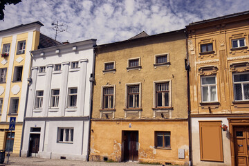 Fototapeta premium Old houses with different colored facades. Street with old colorful houses. Decorative facade, street, shot without people. Doors, windows, blue sky with white clouds.