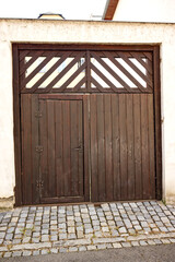 Wooden gate with doors. Old wooden door. Decorative door, wall with light facade. Lines, boards, natural material, entrance, entrance, door from the house.