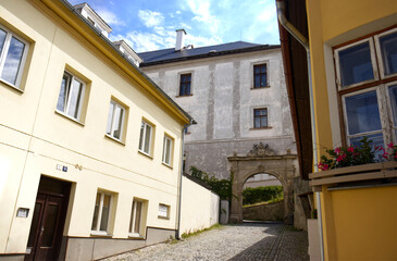 Street in the historic part of the city. Paved sidewalk. Decorative archway to the monastery garden. Historic part of the city, street, summer, travel, arch, gate, houses.