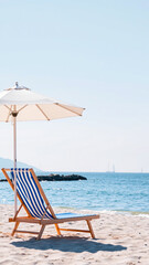 Obraz premium white umbrella shades a striped beach chair on a sunny day