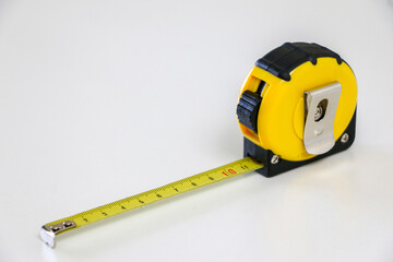 Black and yellow retractable tape measure held in place at 10 cm, on white background, useful tool for measuring length, width and height. Accuracy and precision concept