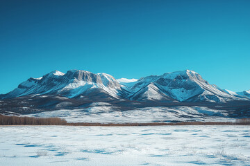 Snow-covered mountains against a clear blue sky in a serene winter landscape, perfect for outdoor activities and nature exploration