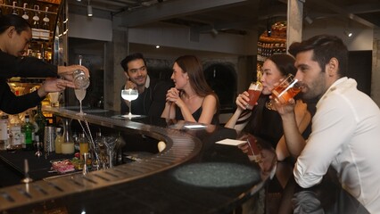 Couple making a toast with cocktail paloma and old fashioned at luxurious bar in lively conversation drinks celebrating a special party at vibrant nightclub while friend drinking Margarita. Vinosity.