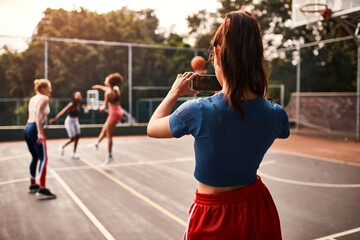 Obraz premium Picture, friends and woman with basketball court, health and practice with training, memory and network. Group, sports and team with game, smartphone and digital app for video recording and fitness