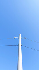 white utility pole against a clear blue sky