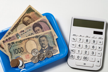 新紙幣とコインと電卓で現金精算のイメージ