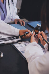 Fototapeta premium Confident representative pharmaceutical showing new medicines to a team of doctor and nurse in hospital. Mature specialist man showing bottle of pills and explaining drug dosage to a group of doctors.