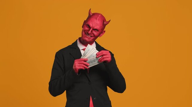 Red devil businessman counting money on yellow background