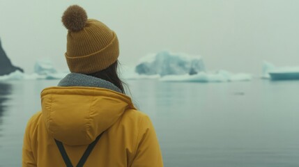 Fototapeta premium Woman in Yellow Jacket Gazing at Icebergs in a Misty Landscape