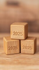 Three wooden blocks stacked, each engraved with the year "2025," set against a softly blurred wooden background.