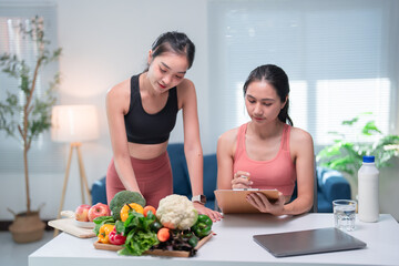 Young nutritionist helping her client create a personalized meal plan using fresh vegetables and...