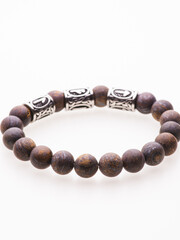 Close up detailed woman's hand with a pearl bracelet holding an interesting handbag in the shape of a silver seashell