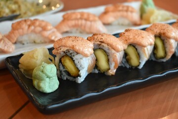 A plate of mentaiko salmon with eel maki sushi with blob of wasabi