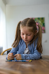 A 5-year-old girl smiles brightly as she draws, showcasing her creativity and joy in art