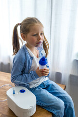 A 5-year-old girl at home uses a nebulizer, taking deep breaths to aid her respiratory health