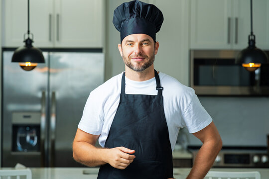 Handsome man chef in uniform cooking in the kitchen. Restaurant menu concept. Hispanic man in baker uniform. Cooking and culinary. Male chef in working uniform, black apron, chef hat.