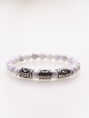 A charming double bracelet in shades of pink, made from natural stone and set against a gray background. The heart charm with cubic zirconia stands out in this close-up top view