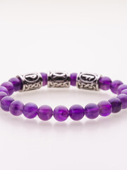 A charming double bracelet in shades of pink, made from natural stone and set against a gray background. The heart charm with cubic zirconia stands out in this close-up top view