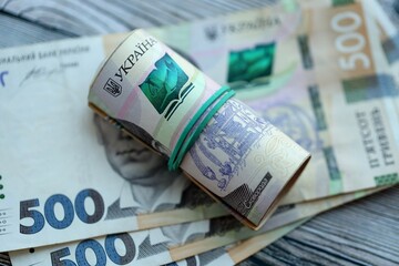 Many five hundred hryvnia money bills lies on wooden background. Ukrainian national currency close...