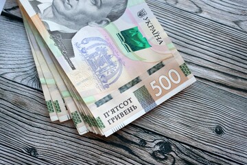 Many five hundred hryvnia money bills lies on wooden background. Ukrainian national currency close...