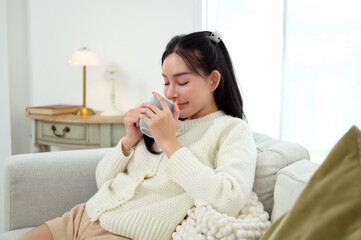 Young asian woman enjoying having coffee in living room at home