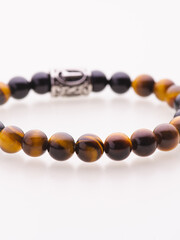 A charming double bracelet in shades of pink, made from natural stone and set against a gray background. The heart charm with cubic zirconia stands out in this close-up top view