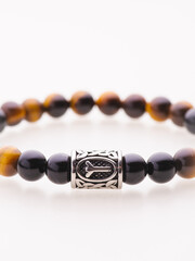 A charming double bracelet in shades of pink, made from natural stone and set against a gray background. The heart charm with cubic zirconia stands out in this close-up top view