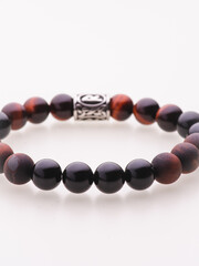 A charming double bracelet in shades of pink, made from natural stone and set against a gray background. The heart charm with cubic zirconia stands out in this close-up top view