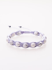 A charming double bracelet in shades of pink, made from natural stone and set against a gray background. The heart charm with cubic zirconia stands out in this close-up top view