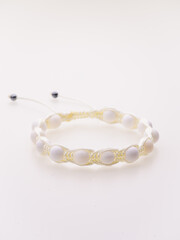 A charming double bracelet in shades of pink, made from natural stone and set against a gray background. The heart charm with cubic zirconia stands out in this close-up top view