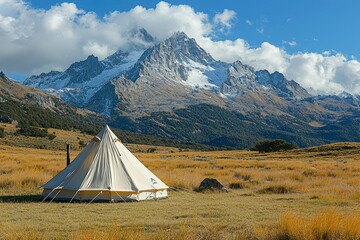 A White Tent in a Field with a Snowy Mountain Range in the Background