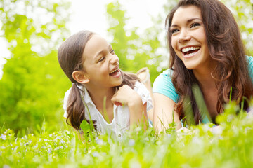 Mother, girl and relax on grass, conversation and outdoor for family bonding on vacation. Mama, support daughter and countryside trip for love on weekend, laughing and lying together on holiday