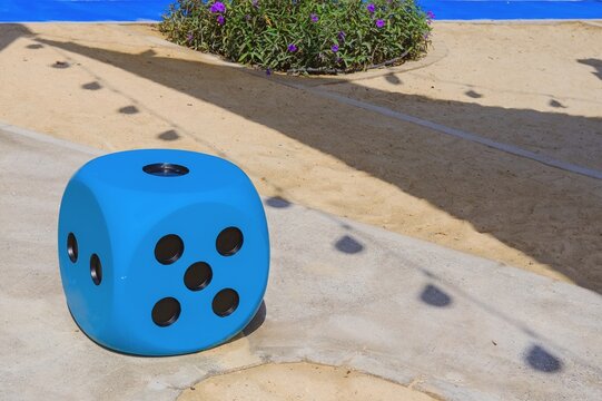  Blue huge gambling cube as a creative decision for urban furniture. Oversize giant blue dice shaped chair with five dots for game at the playground.