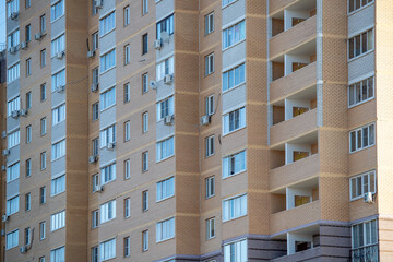 A large brown building with many windows and air conditioners