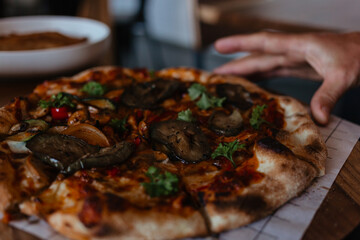 Man's hand takes a piece of delicious vegetarian pizza. Vegetable pizza with cheese and parsley