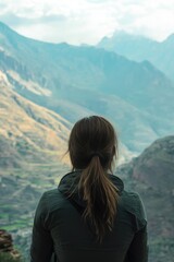 Naklejka premium Woman standing at high vantage point in Andes, gazing over valley and mountains, appreciating natural beauty.
