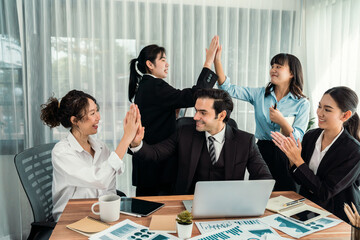 Group of happy businesspeople in high five gesture and successful efficient teamwork. Diverse race office worker celebrate after made progress on marketing planning in corporate office. Habiliment