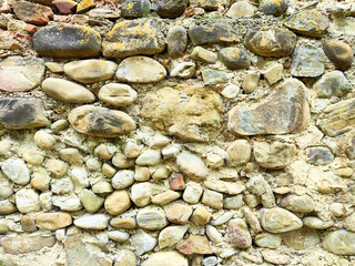 Textured stone wall composed of various sizes and shapes of pebbles located in a natural setting